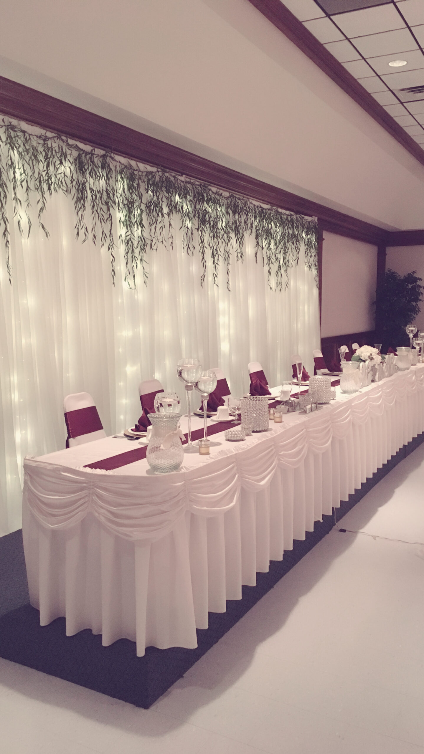 At the event center, a beautifully designed table features maroon decor and an elegant side display.