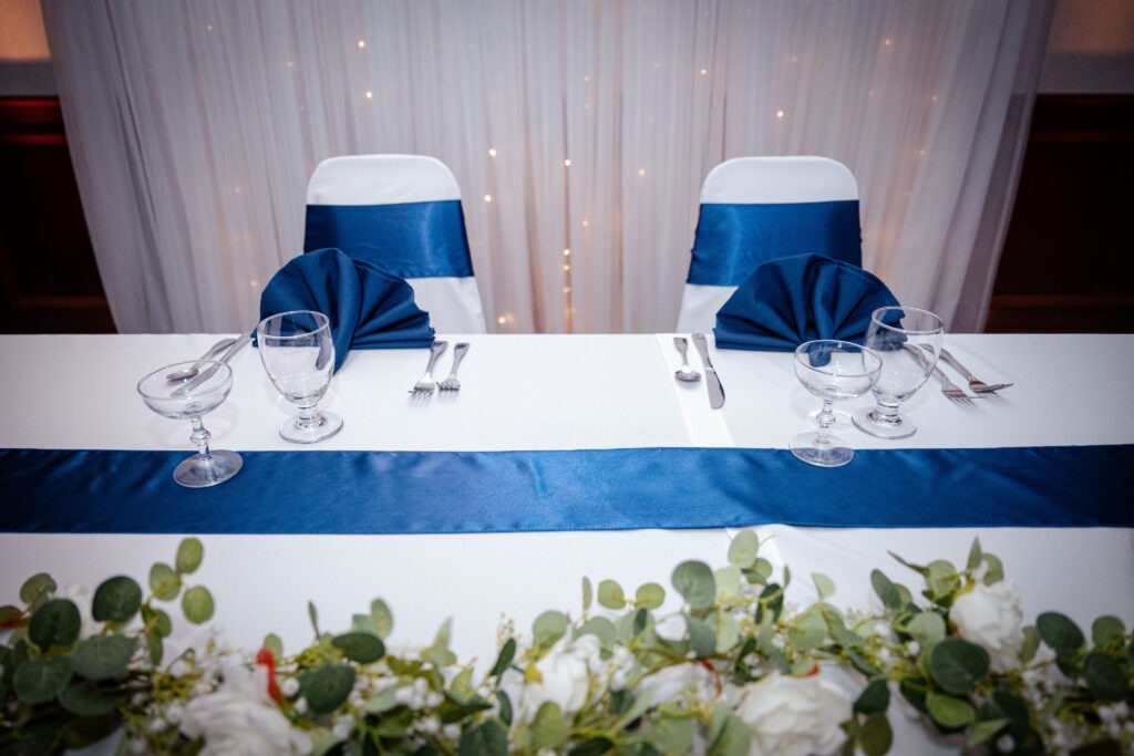 Elegant dining setup featuring a white table adorned with a blue satin runner