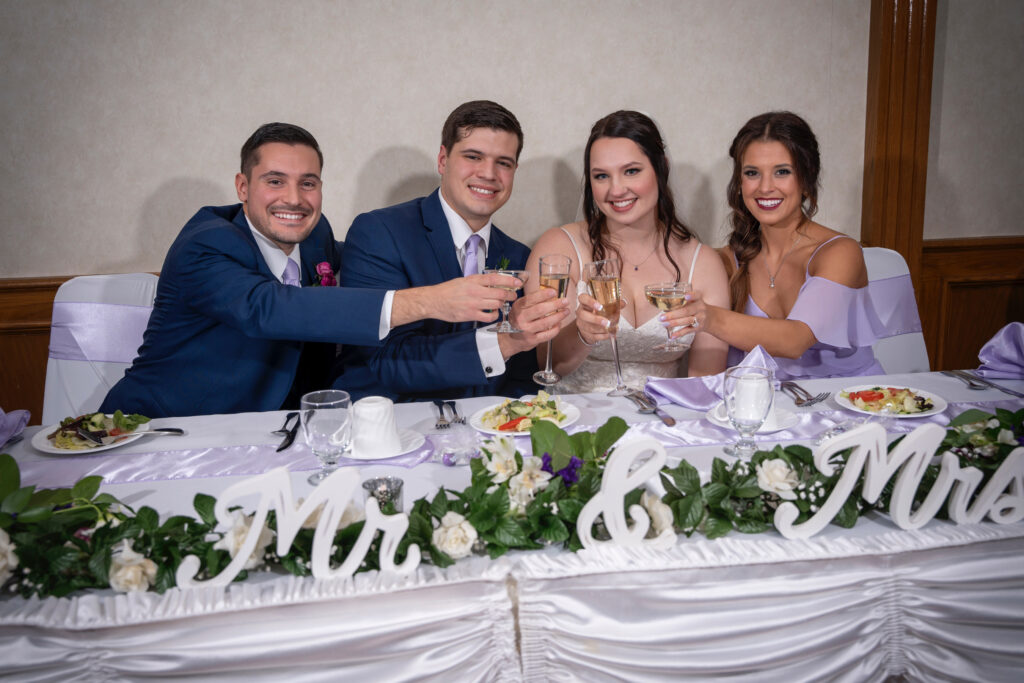 Four friends toast with champagne at a wedding reception, smiling joyfully