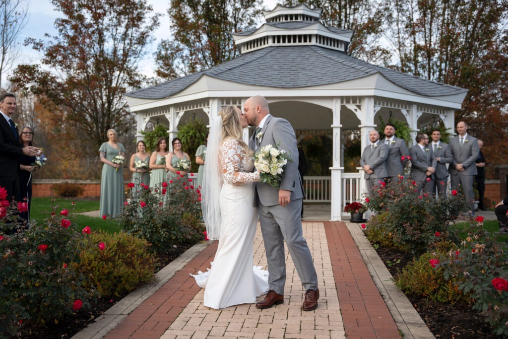 Bride and groom kiss under a gazebo during their wedding ceremony