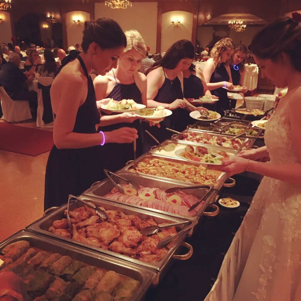Bridesmaids in navy dresses serve themselves from a buffet at a wedding reception